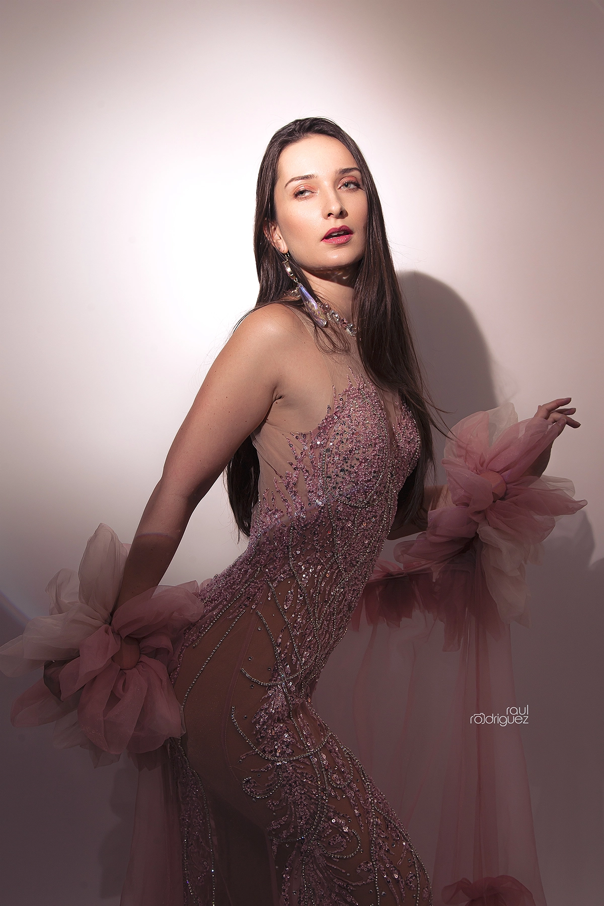 Retrato de plano medio lateral con vestido rosa de pedrería y grandes aplicaciones de tul.