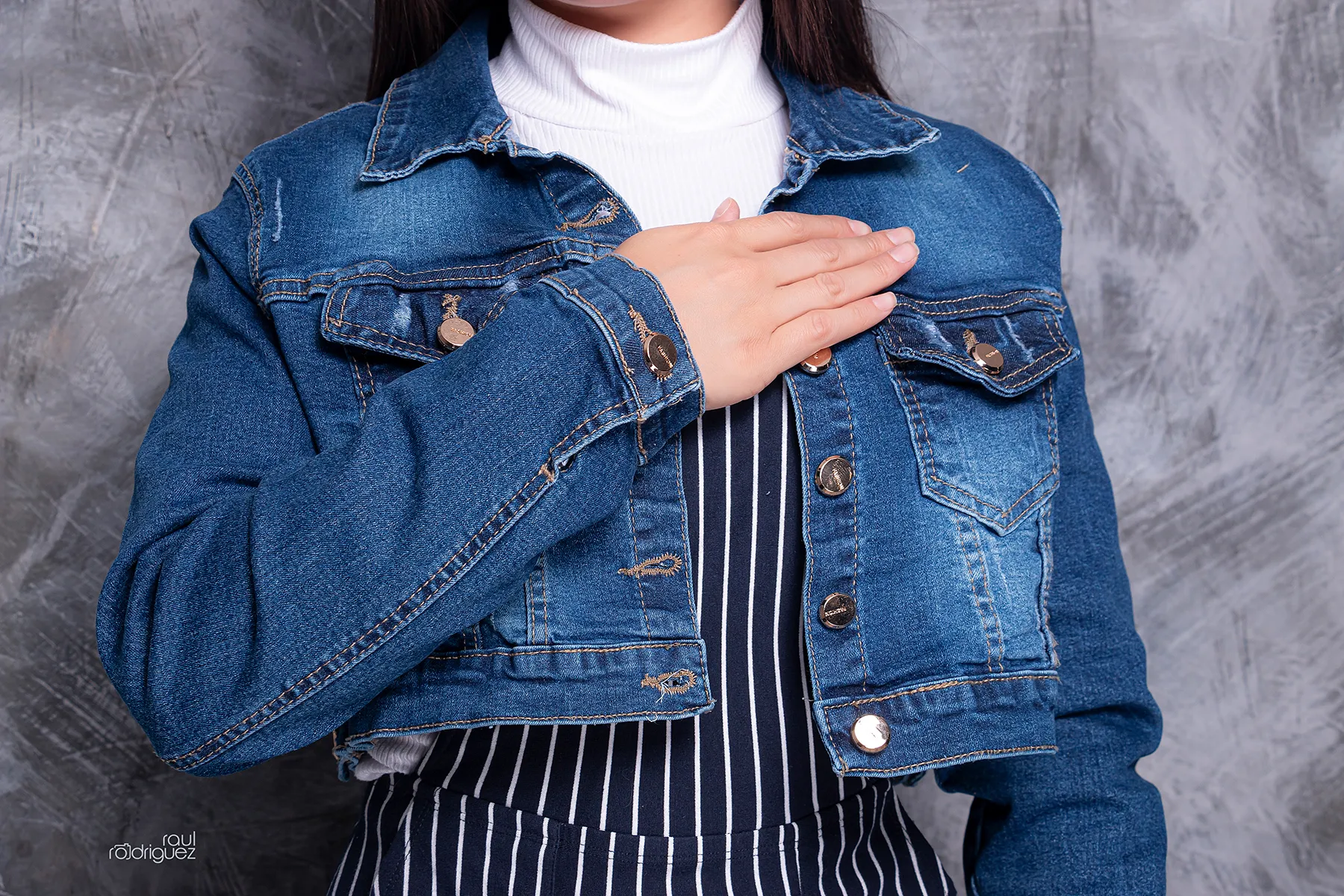 Acercamiento a una chamarra corta de mezclilla azul abierta, con cuello, bolsillos de pecho, botones metálicos y costuras contrastantes.